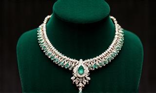 Ein exquisites Smaragd- und Diamantcollier auf einem Samtdisplay.